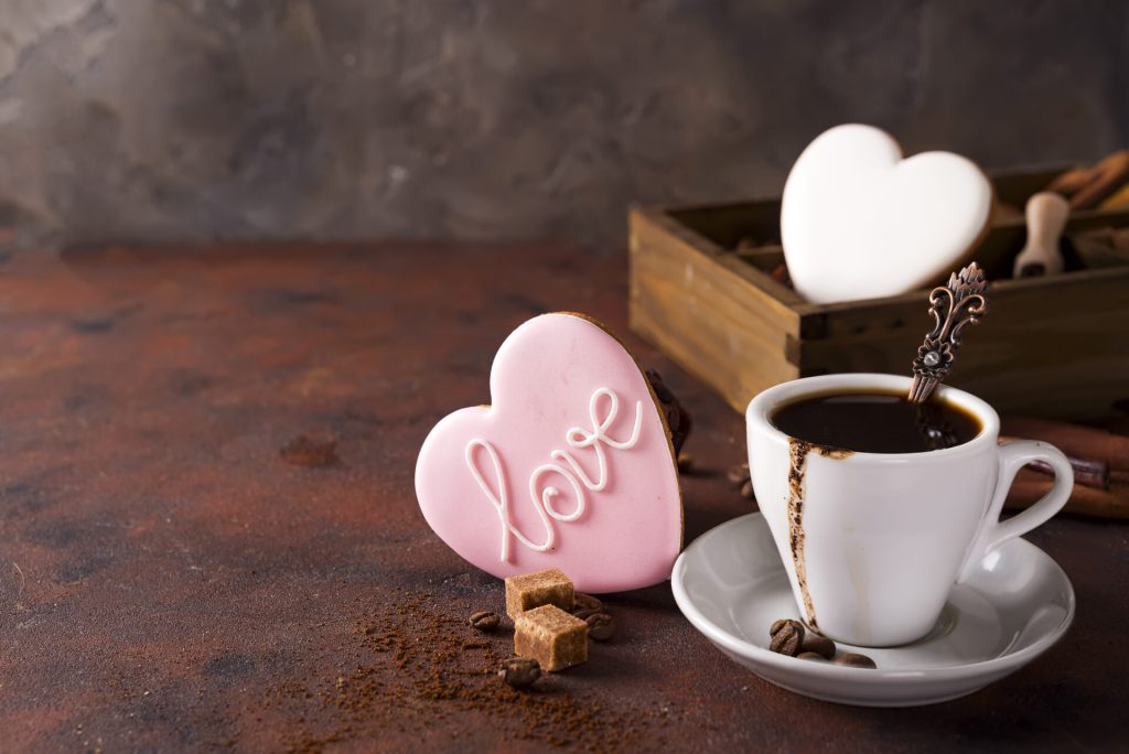Cup of coffee with cooffee beans, wooden box with grains of coffee and spices, cookies on a stone background