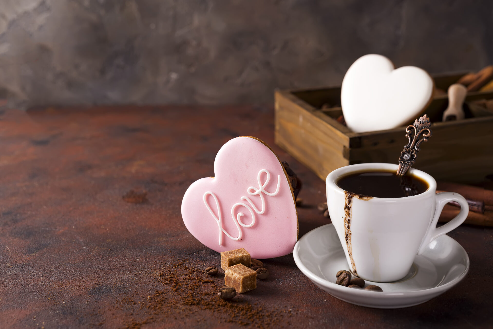 Cup of coffee with cooffee beans, wooden box with grains of coffee and spices, cookies on a stone background